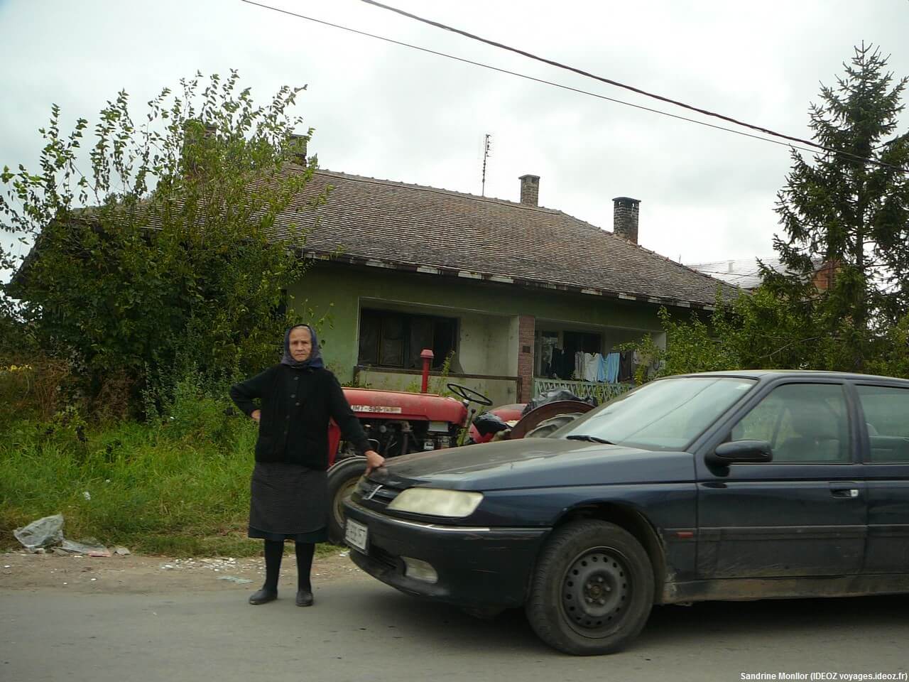 Vieille dame près d'une voiture sur la route à la sortie de Umraci en Serbie centrale