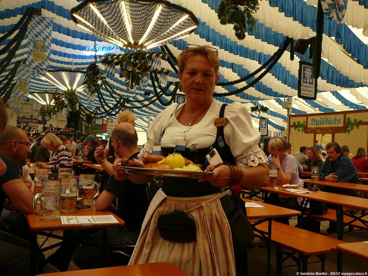 Serveuse en habits bavarois apportant un plat typique de viandes et knodels à la fête de la bière de Munich