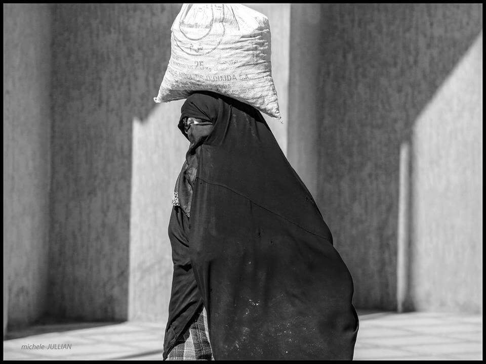 Rissani femme marocaine portant sur sa tête une lourde charge