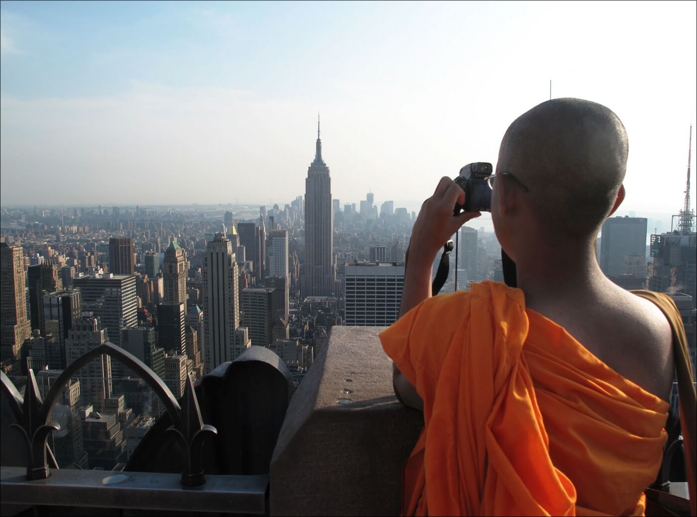 moine bouddhiste prenant de la hauteur pour photographier la ville de new york