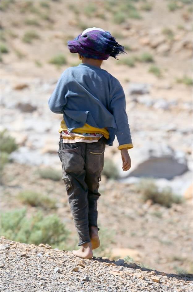 enfant nomade au maroc marchant sans chaussure ruban dans le vent