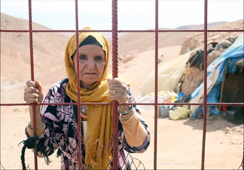 femme berbère derrière des grilles dans un bivouac au maroc