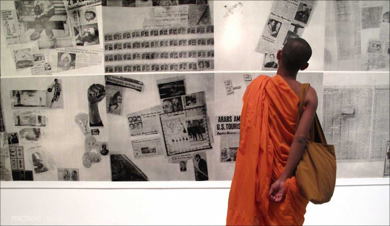 moine bouddhiste en train de découvrir une exposition de coupures de presse à new york