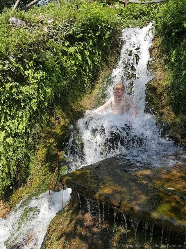 Enfant dans une petite cascade près des anciens moulins de Roški slap à Krka