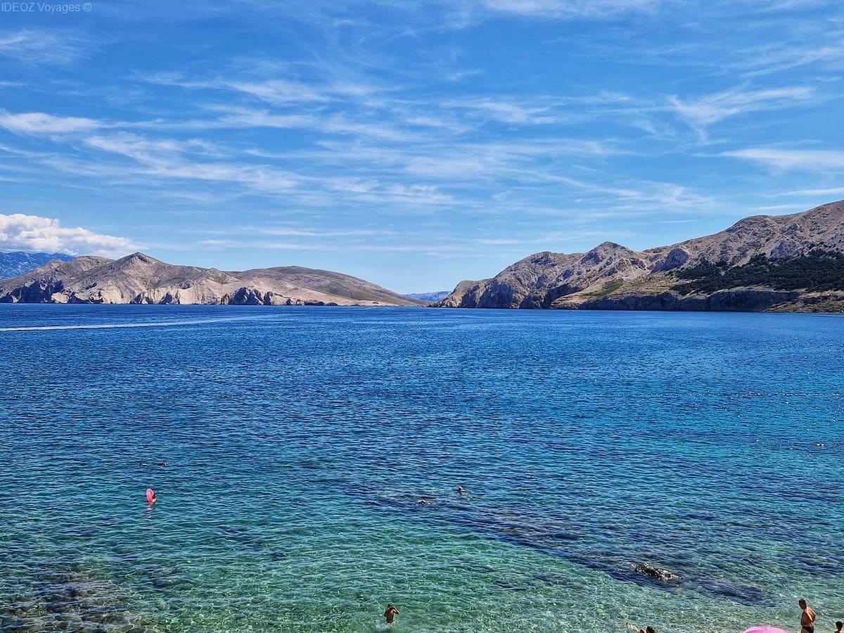Vue sur la baie de Baška et l’île rocheuse de Prvić depuis la plage