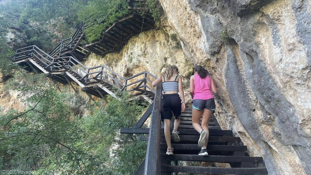 Deux randonneuses montent les escaliers aménagés contre la falaise vers la grotte Oziđana