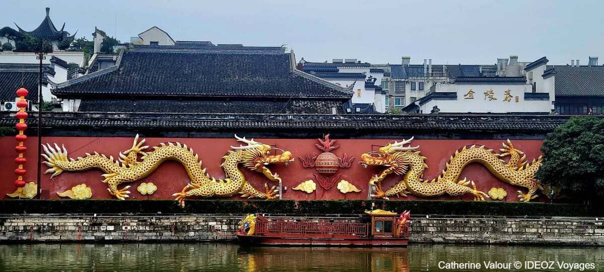 Deux grands dragons dorés décorant un mur rouge au bord d'un canal à Nankin